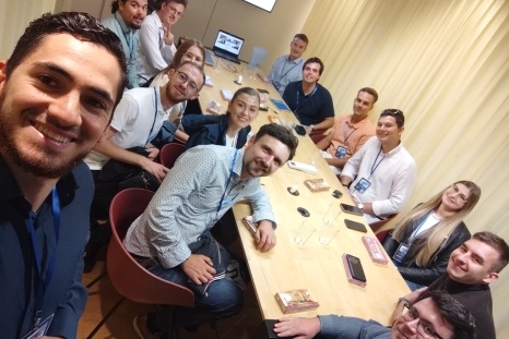 Gruppenselfie von Teilnehmern an einem Meeting an einem Tisch.