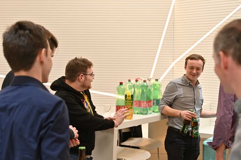 Gruppe junger Menschen mit Getränken in einer fröhlichen Gesprächssituation.