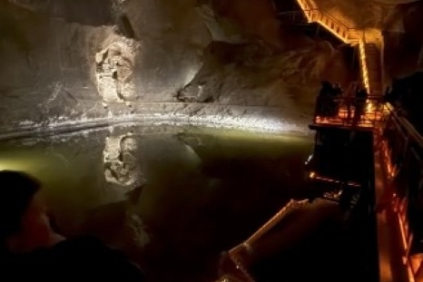 Ein unterirdischer Raum mit einem stillen Wasserbecken und beleuchteten Felswänden.