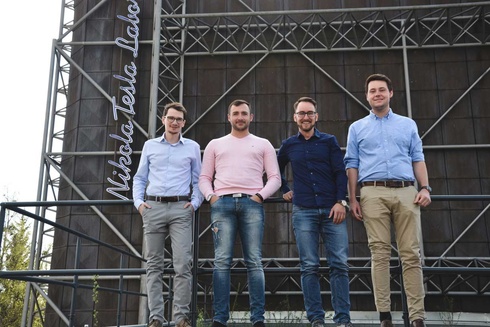 Vier Männer stehen nebeneinander vor einem Gebäude mit der Aufschrift "Nikola Tesla Lab".