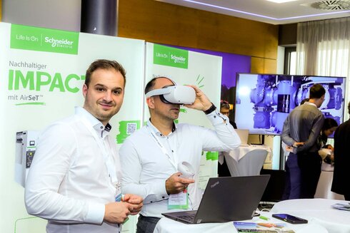 Zwei Männer präsentieren eine VR-Technologie auf einer Messe.
