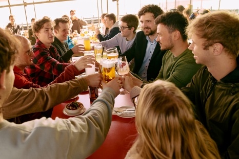 Freunde stoßen mit Getränken an einem Tisch in geselliger Runde an.