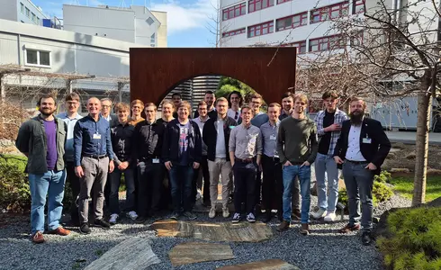 Gruppe von Männern posiert vor einem Metallbogen in einem Garten.