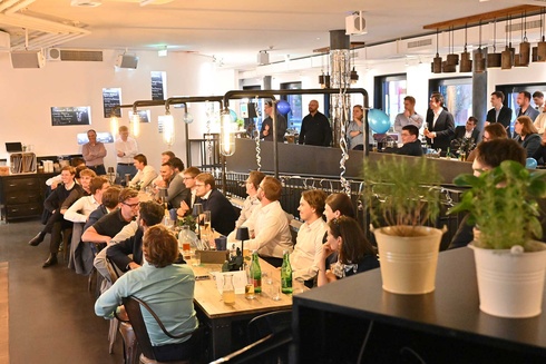 Eine Gruppe von Menschen sitzt an Tischen in einem modernen Restaurant.