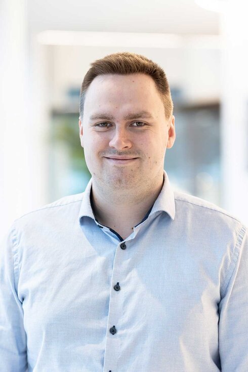 Portrait eines lächelnden Mannes in einem hellen Hemd.