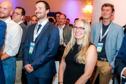 Preisträgerin, inmitten von Männern, freut sich über ihren Erfolg