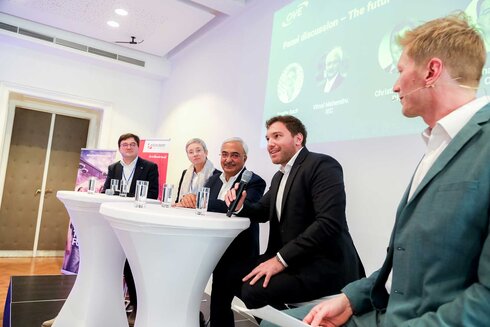 Podiumsdiskussion mit mehreren Rednern zu Zukunftsthemen an einem Tisch.