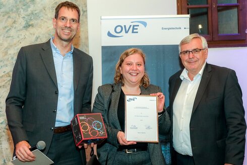 Preisübergabe, zwei Männer mit einer Frau in der Mitte