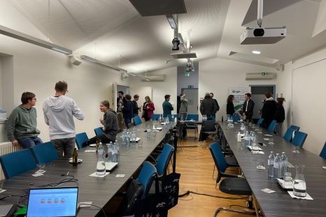 Ein Meetingraum mit Menschen, Tischen und Wasserflaschen.