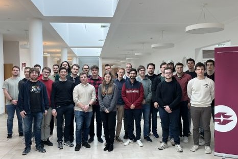 Gruppe von jungen Erwachsenen lächelt in einem modernen Raum.