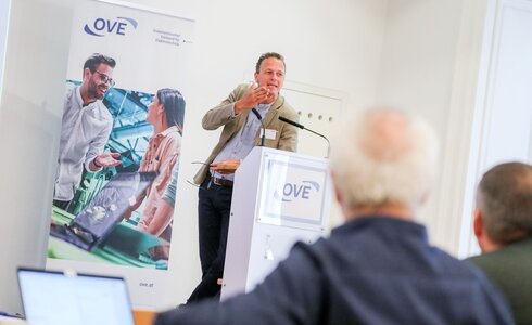 Ein Mann spricht an einem Podium vor Publikum auf einer Veranstaltung.