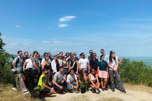Gruppe von Menschen posiert zusammen im Freien mit Aussicht auf das Wasser.