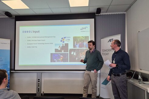 Zwei Personen präsentieren Inhalte auf einer Leinwand während einer Veranstaltung.