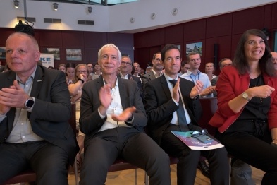 Zuhörende Personen applaudieren in einem Konferenzraum.