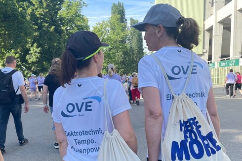 Zwei Frauen in T-Shirts gehen auf einem Event.