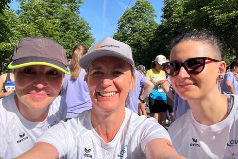 Drei Frauen machen ein Selfie vor einem Laufereignis im Freien.