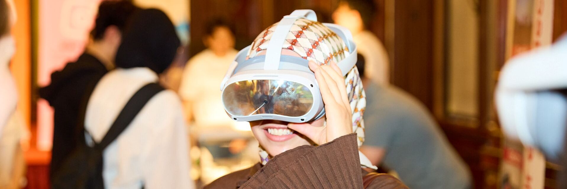 Eine Person trägt eine VR-Brille und lächelt in einer Menschenmenge.