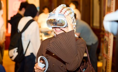 Eine Person trägt eine VR-Brille und lächelt in einer Menschenmenge.