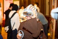 Eine Person trägt eine VR-Brille und lächelt in einer Menschenmenge.