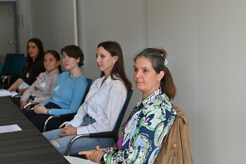 Fünf Frauen sitzen an einem Tisch und hören aufmerksam zu.