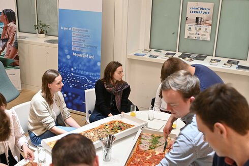 Gruppe von Menschen, die gemeinsam an einem Tisch Essen teilen.