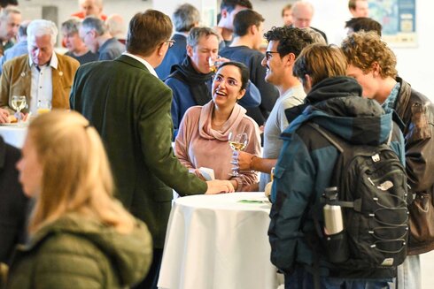 Eine Gruppe von Menschen unterhält sich fröhlich bei einem Stehempfang.