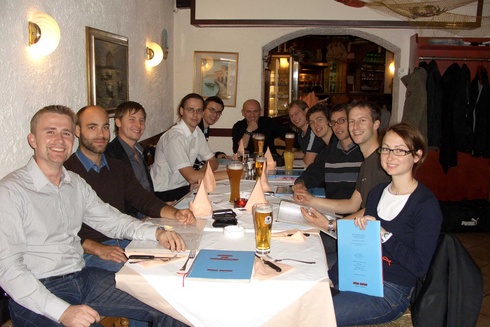 Gruppe von Männern und Frauen sitzt zusammen an einem Tisch in einem Restaurant.