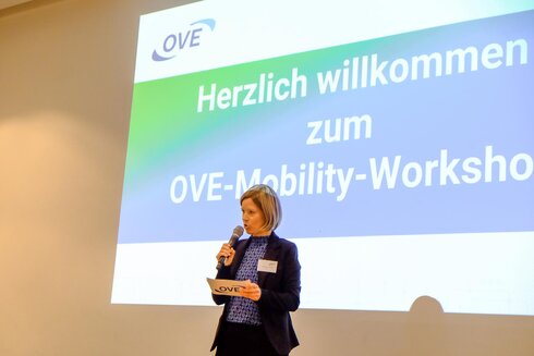 Frau spricht willkommen beim OVE-Mobility-Workshop vor einer Präsentationsfolie.