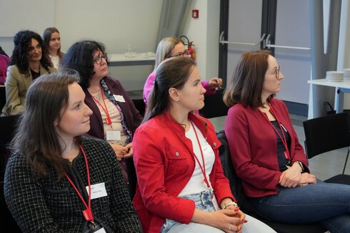 Vier Frauen hören aufmerksam bei einer Veranstaltung zu.