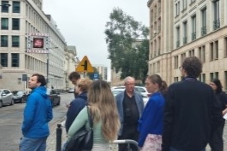 Gruppe von Personen steht an einer Straßenecke in städtischer Umgebung.