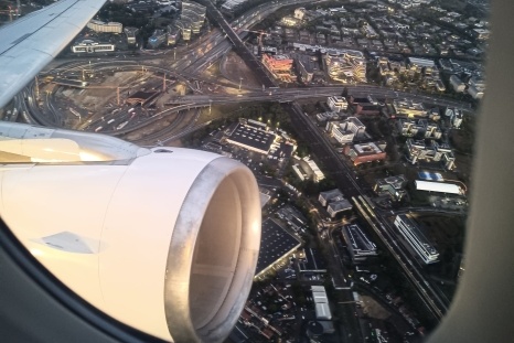 Blick aus dem Flugzeugfenster auf die Stadt und den Triebwerk.