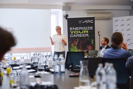 Eine Frau präsentiert vor einem Banner mit der Aufschrift "Energize Your Career".