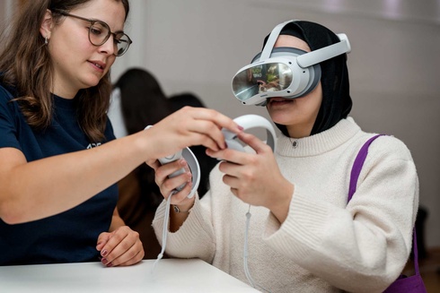 Eine Frau mit VR-Brille erhält Unterstützung bei der Nutzung von VR-Geräten.