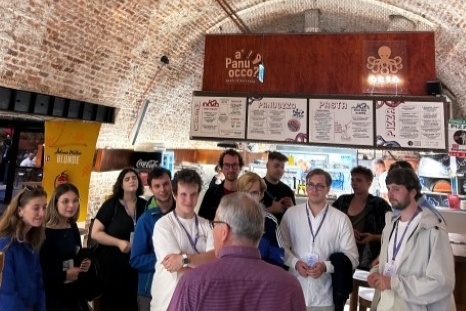 Eine Gruppe von Menschen hört einem Referenten in einem Cafe aufmerksam zu.