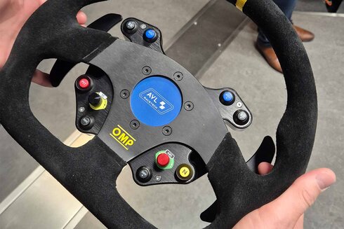 Ein Rennlenkrad mit verschiedenen Bedienelementen in Händen gehalten.