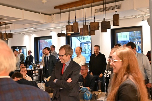 Menschen in formeller Kleidung lachen und unterhalten sich in einem Restaurant.