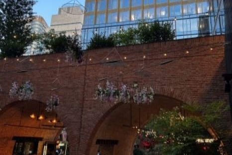 Gemütlicher Außenbereich eines Restaurants mit Pflanzendekoration und einer Backsteinmauer.