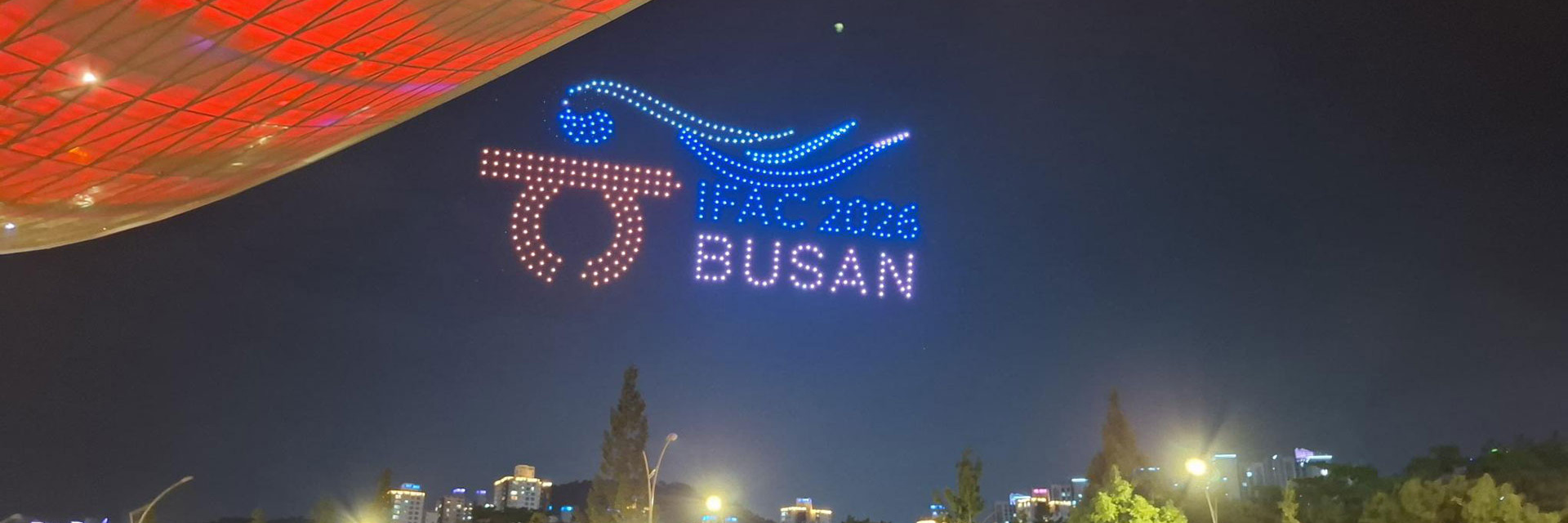 Lichtershow mit dem Text „IAAF 2023 BUSAN“ am Nachthimmel.