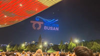 Lichtershow mit dem Text „IAAF 2023 BUSAN“ am Nachthimmel.