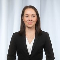 Portrait einer Frau in schwarzem Anzug vor einem hellen Hintergrund.