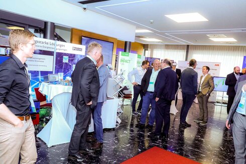 Menschen in Businesskleidung interagieren auf einer Fachmesse oder Konferenz.