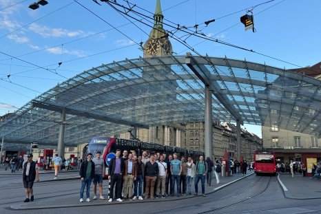 Gruppe von Menschen vor einem Glaskonstrukt am Bahnhof.