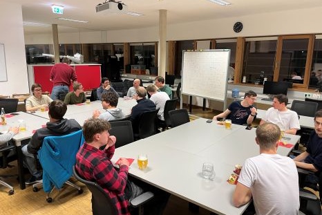 Gruppe von Menschen versammelt an einem Tisch, ungezwungene Gespräche und Snacks.