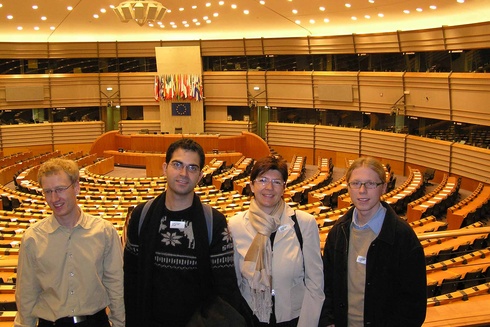 Vier Personen stehen in einem großen Sitzungssaal des Europäischen Parlaments.