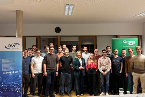 Eine Gruppe von 20 Personen steht vor Bannern in einem Raum.