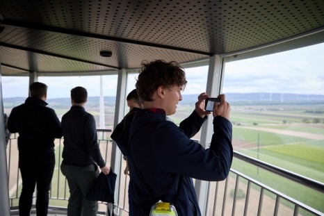 Junger Mann fotografiert von einer Aussichtsplattform in die Landschaft.