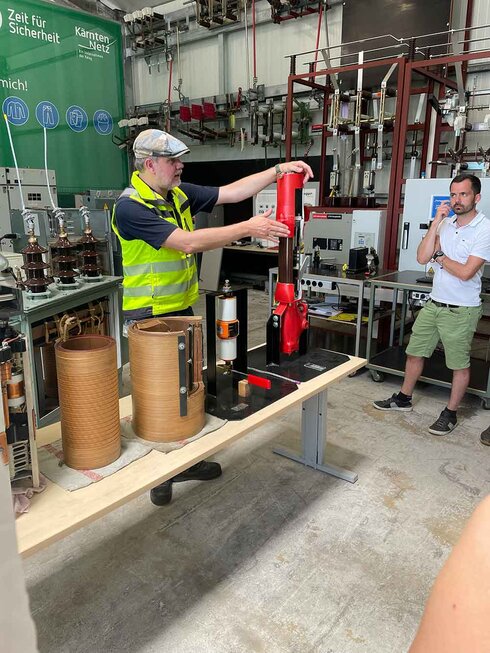 Ein Mann mit Weste demonstriert ein Gerät in einem Laborumfeld.