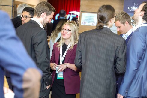 Eine Gruppe von Menschen bei einer Networking-Veranstaltung, eine Frau spricht mit Kollegen.