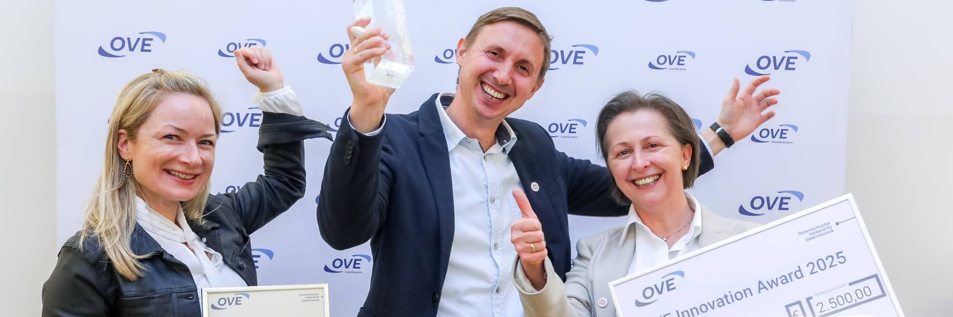 Drei Personen feiern den Gewinn des OVE Innovation Award 2025.