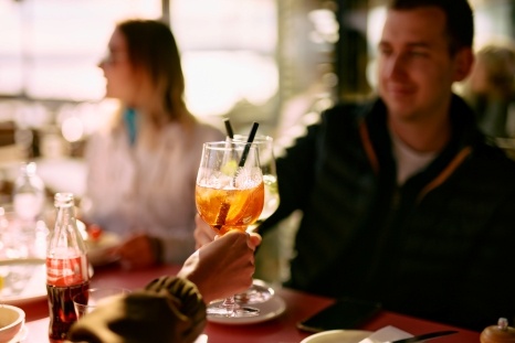 Ein Mensch stößt mit einem Glas Getränk an.